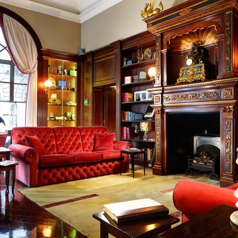 Traditional family room design with large elegant fireplace and red velvet sofas