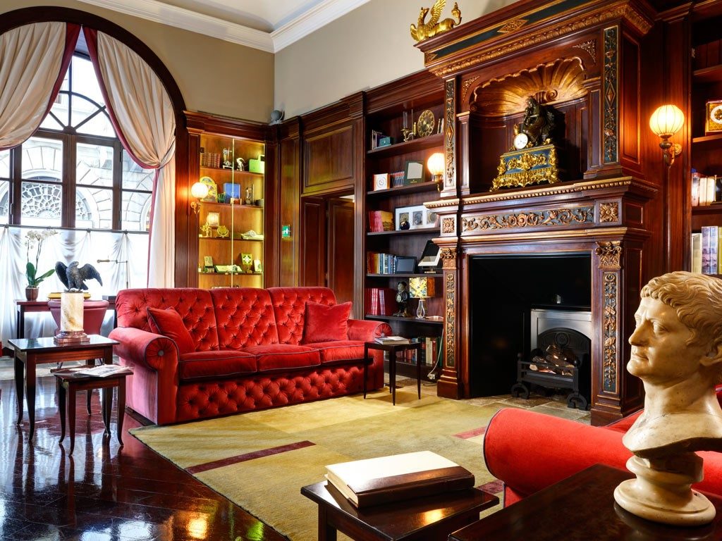 Traditional family room design with large elegant fireplace and red velvet sofas