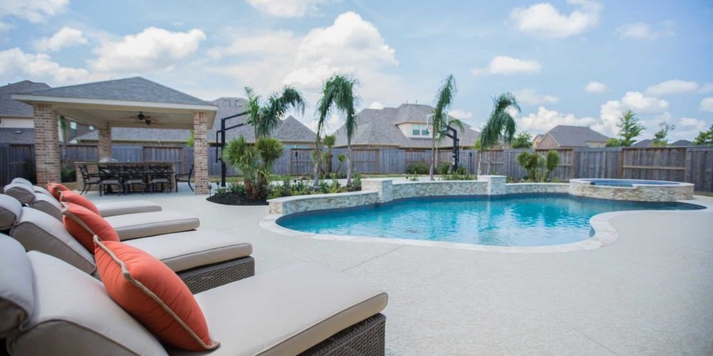 Outdoor area design with beige lounge chairs and an in-ground pool