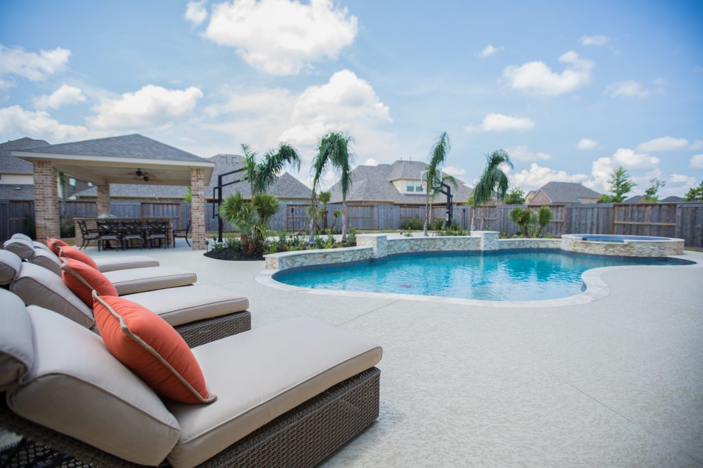 White patio design with in-ground pool and orange accent pillows