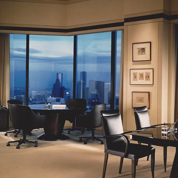 Beige office with dark furniture and large windows with a city skyline view