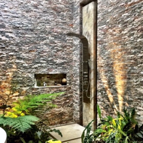 Outdoor waterfall shower surrounded by shrubs and plants