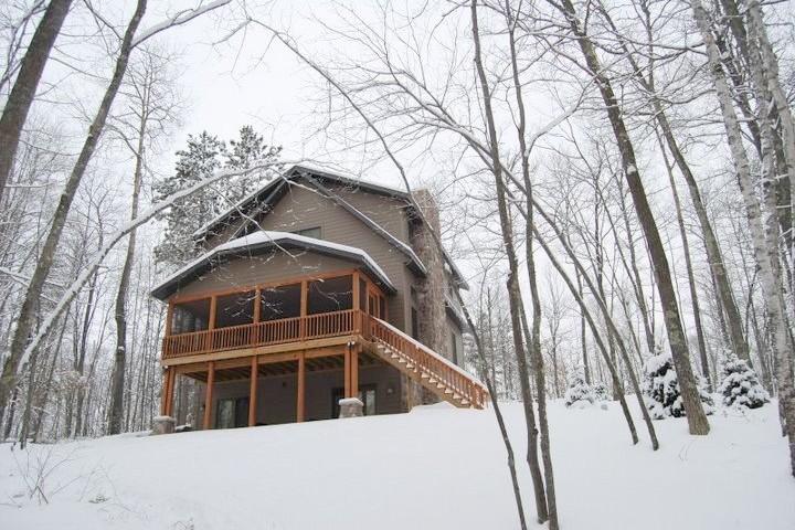 Exterior of a lake house on a mountain with snow falling