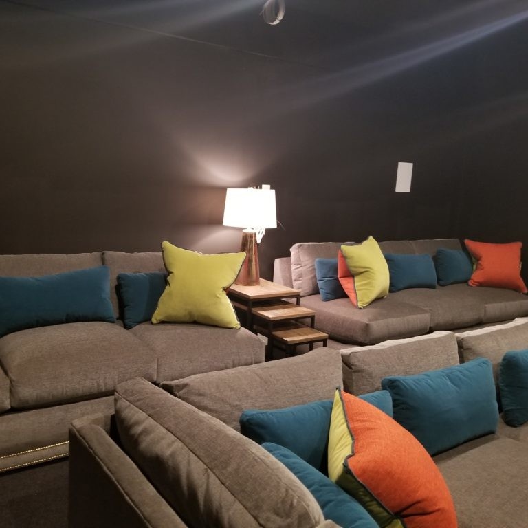 Three gray sofas with primary colored accent pillows