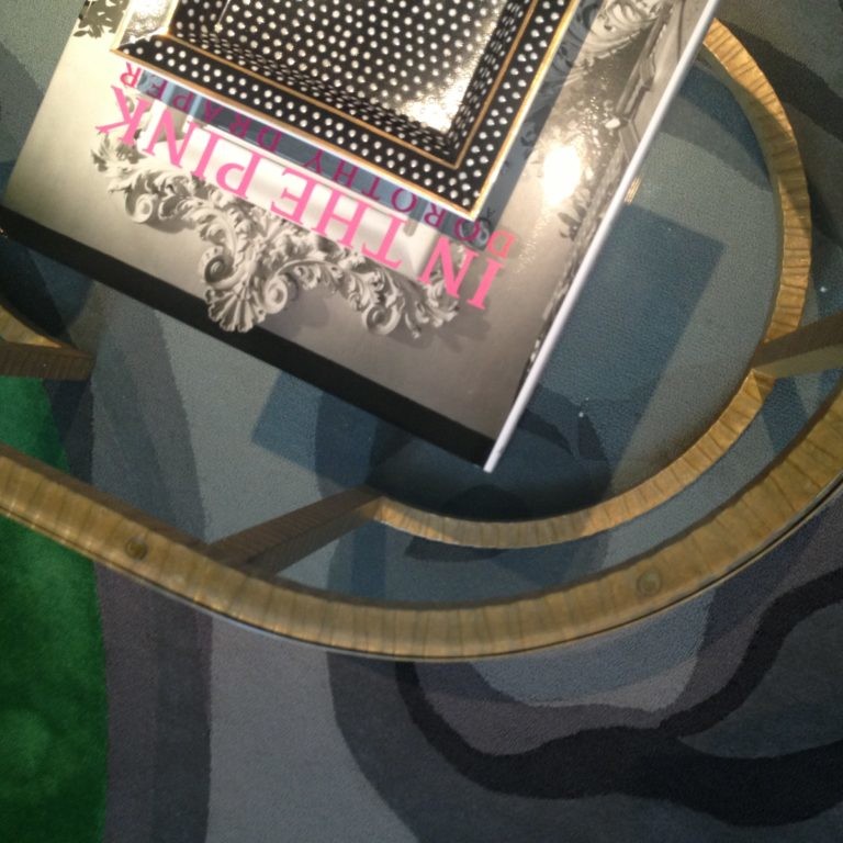 Gold-trimmed glass coffee table on top of a green and gray abstract rug